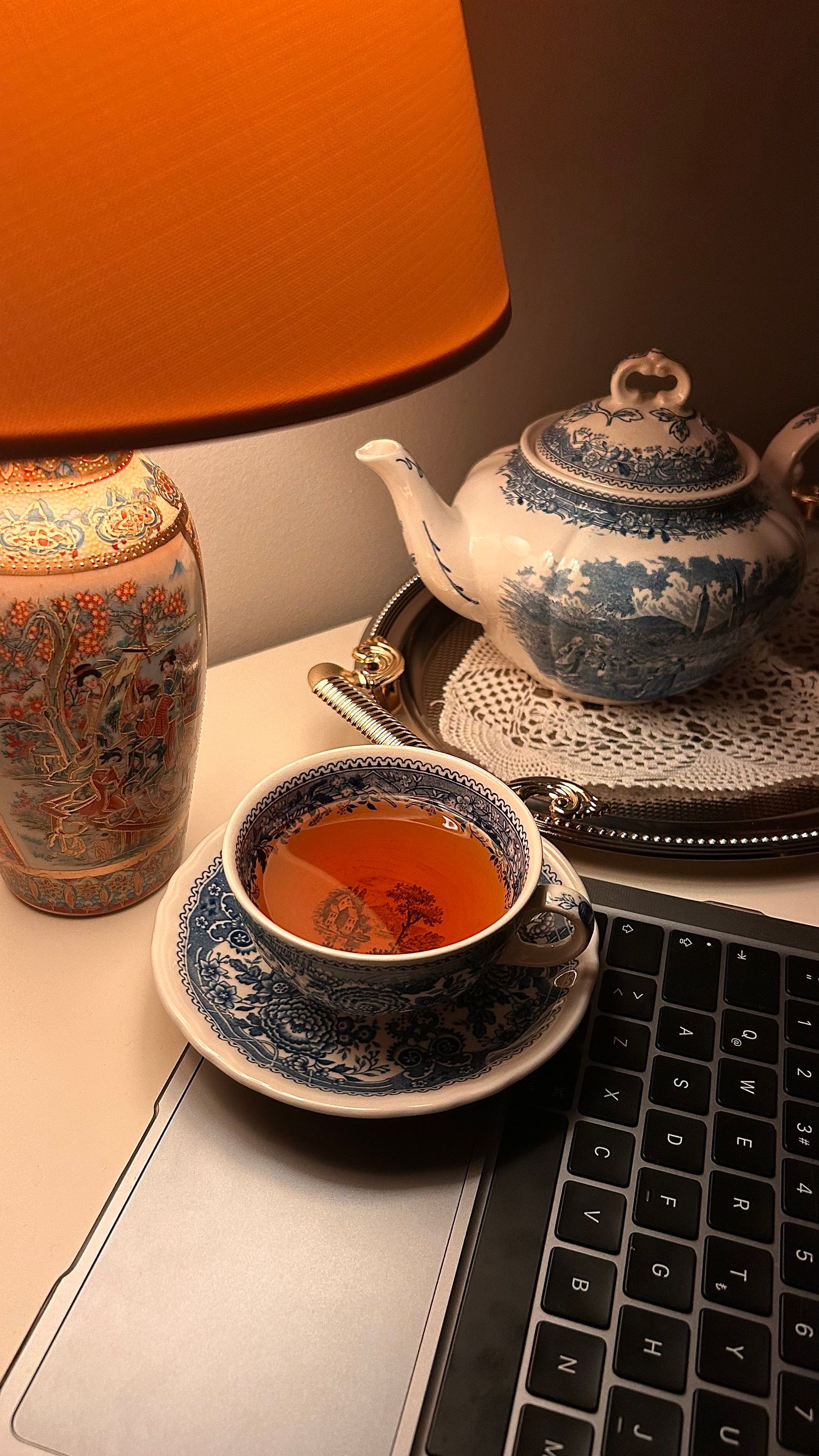 灯下的茶杯、茶壶和还开着的键盘